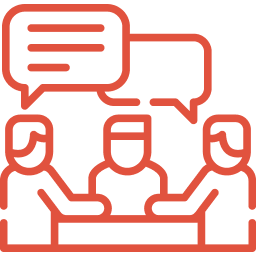 Red outline icon of three people sitting at a table, engaging in discussion, with two large speech bubbles above their heads, indicating conversation or collaboration.